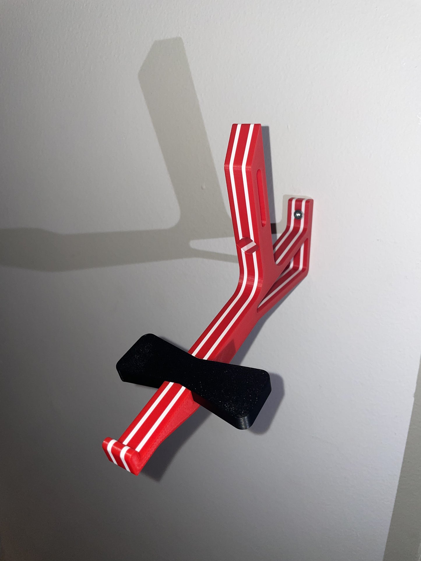 Red, white, and red angled cap butler assembly mounted on a white wall without  a cap