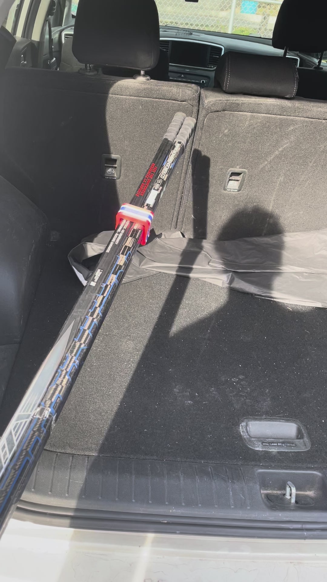 Easily loading clipped hockey sticks into a car's trunk